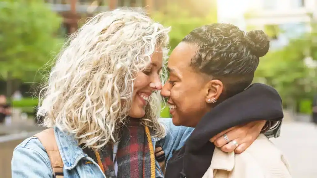 Two women sharing a joyful moment outdoors, embracing each other.