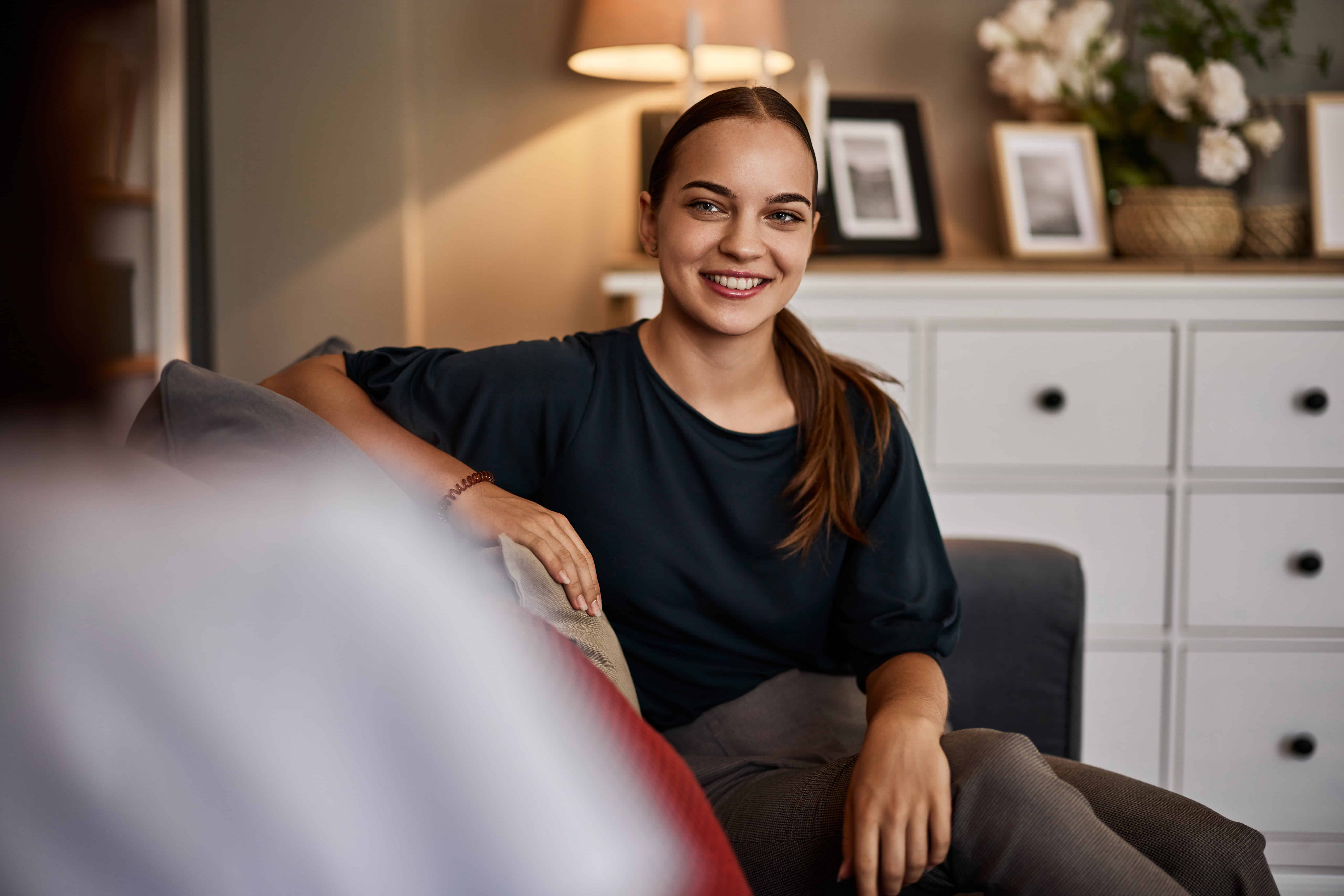 A man smiling while sitting on a couch with her therapist for the topic how much does rehab cost.
